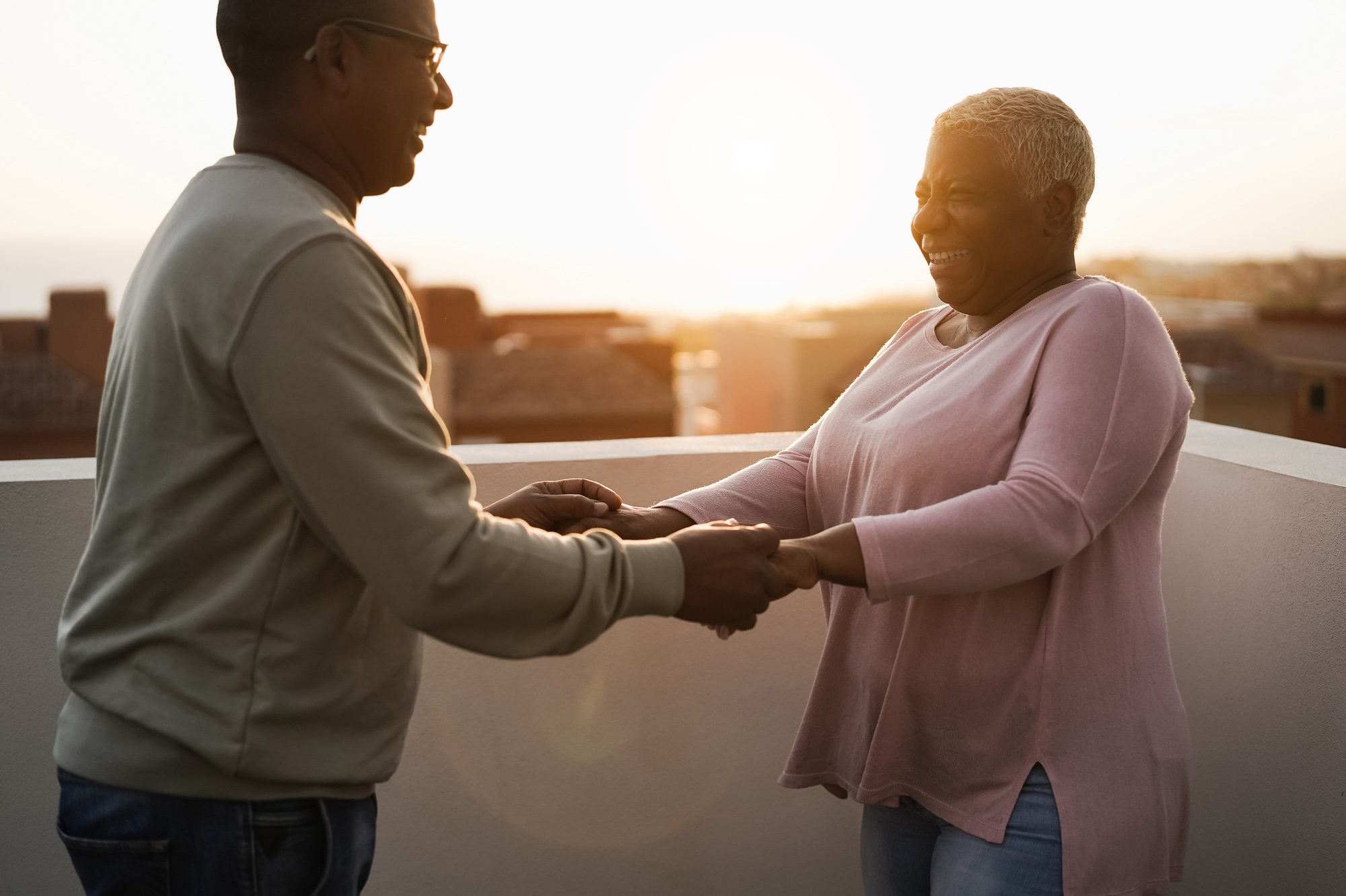 Happy black couple dancing outdoors at summer sunset - Focus on woman face